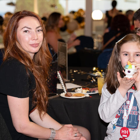Un participant adulte et un enfant sont assis à une table de réception, réunis pour un moment calme pendant l’événement.