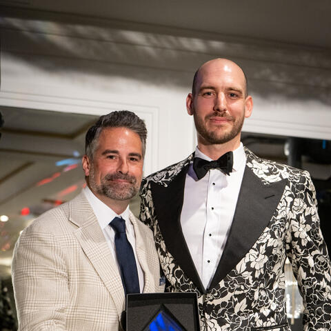 Un participant pose avec un prix, rapproché d'une autre personne pour une photo lors d’un moment festif pendant un événement-bénéfice formel.