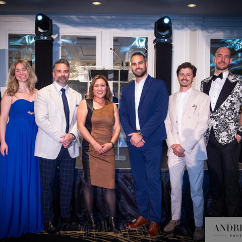 Des participants se rassemblent sur scène en tenue de soirée, côte à côte, alors qu’ils sont reconnus lors d’un événement-bénéfice.